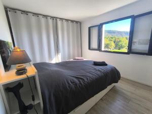 a bedroom with a bed with a lamp and a window at Entre Bois et Lumiere in Le Brusquet