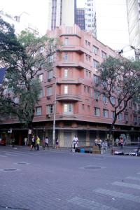 a pink building with people walking in front of it at Estoril Hotel in Belo Horizonte