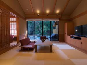 a living room with a couch and a table and a tv at Tsukiyominoza in Ise