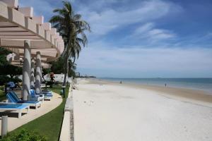 a beach with chaise lounges and the ocean at Hua Hin Loft Managed by Loft Group in Hua Hin