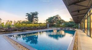 a swimming pool with tables and chairs next to a building at KS HOTEL in Ban San Ton Kok