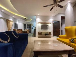 a living room with a blue couch and a ceiling fan at Villa Avanora by DanCenter in Arpora