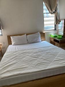 a large white bed in a room with two windows at nhà trọ my anh in Hanoi