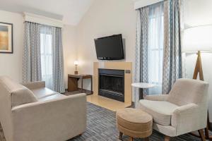 a living room with a couch and chairs and a television at MainStay Suites St Louis - Galleria in Richmond Heights