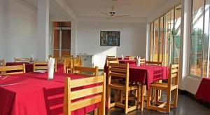 a dining room with red tables and wooden chairs at OYO 246 Roy Villa Beach Hotel in Paiyagala North