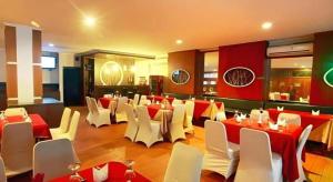 a restaurant with red and white tables and white chairs at Alexander Hotel Tegal in Tegal