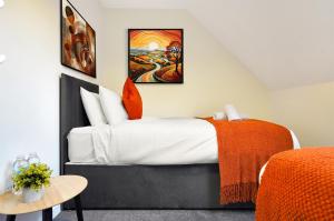 a bedroom with a large bed with an orange blanket at King Size beds, CCTV parking , Discounts in Shinfield