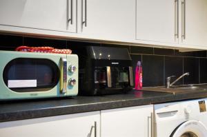a microwave sitting on a kitchen counter next to a sink at 3-Bedroom 5-Bed Flat King Room Free Parking Near Reading & M4 Work Stays in Shinfield