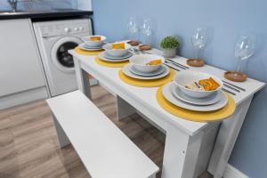 a white table with plates and bowls of food on it at 2 King or 4 Single Beds Workspace Walk to Bedford Station Parking Wi-Fi in Bedford +8 photos