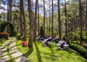 a garden with tables and chairs in the grass at Le Monet Hotel in Camp John Hay