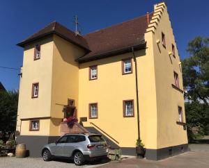 una iglesia amarilla con un coche aparcado delante en Altes Vogtshaus, en Weil am Rhein