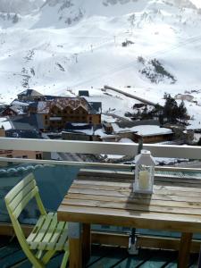 a table and chairs on a balcony with a snow covered mountain at Petit studio lumineux vue montagne in La Mongie
