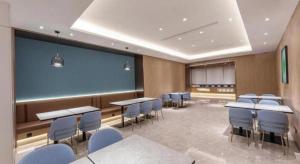 a conference room with tables and chairs and a large screen at GreenTree Inn JiangSu NanJing South Railway Station South Square Express Hotel in Jiangning