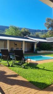 - deux chaises assises devant une maison dans l'établissement Harties Is Africa Safari Lodge, à Hartbeespoort