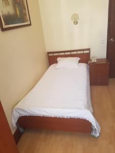 a bed in a room with a white bedspread at Residencial Central in Caldas da Rainha