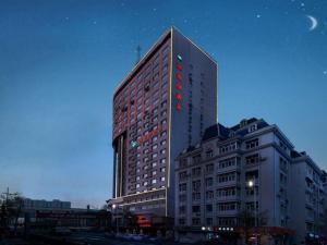 a tall building with red lights on top of it at Vienna Hotel Harbin Central Avenue in Harbin