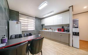een keuken met een tafel, stoelen en een koelkast bij Tongyeong Daon Hotel in Tongyeong
