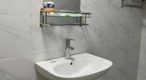 a white sink in a white tiled bathroom at 7 Days Inn Tianjin Zhongshan Road North Station in Tianjin