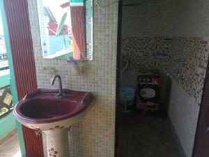 ein Badezimmer mit einem lila Waschbecken und einem Spiegel in der Unterkunft Prince Home Stay in Jāmb