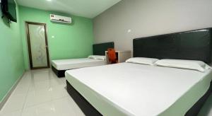 zwei Betten in einem Zimmer mit grünen Wänden in der Unterkunft OYO 90789 Stutong Point in Maong Bazaar