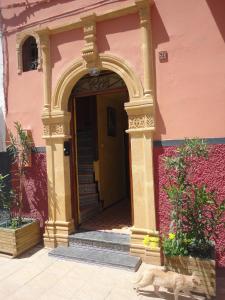 une entrée à un bâtiment rose avec une arche dans l'établissement Dar Yanis, à Rabat