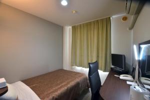 um quarto de hotel com uma cama e uma secretária com um computador em Isahaya Daiichi Hotel em Isahaya