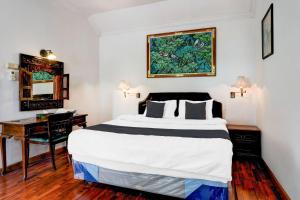 una cama en una habitación con un escritorio y una cama sidx sidx sidx en Hotel O Bandung near Stadion Siliwangi formerly The Ethnic Hotel Bandung, en Bandung 21 fotos más