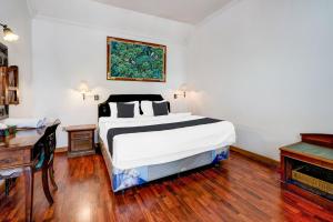 Un dormitorio con una cama, una mesa y un escritorio. en Hotel O Bandung near Stadion Siliwangi formerly The Ethnic Hotel Bandung, en Bandung