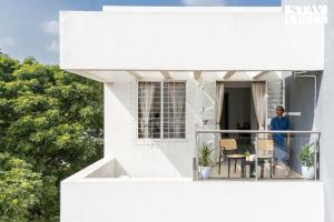 a woman standing on the balcony of a white house at StayVista Residences at Baner - Balewadi with Purifier in Pune +46 photos