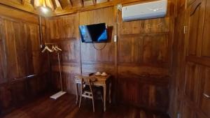 Cette chambre dispose d'une table et d'une télévision sur un mur en bois. dans l'établissement Griya Taman by Sundari Hospitality, à Tumbak Bayuh