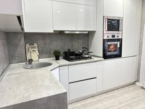 a white kitchen with a sink and a stove at Sky Apartment Bolashak in Aktobe +9 photos