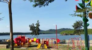 a park with a playground next to the water at Riverine Garden Hotel in Kampong Gong Pauh