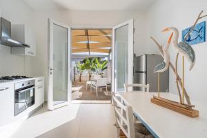 une cuisine avec des comptoirs blancs et une salle à manger avec un patio dans l'établissement Lèvè – Sea Nature Stay, à Torre Lapillo