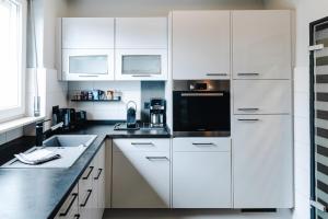 a white kitchen with white cabinets and a sink at SchönHier in Westerburg