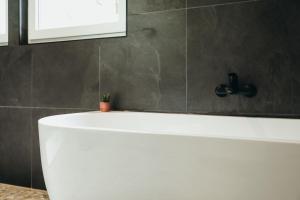 a white bath tub in a bathroom with a window at La Source du Lodji by WelcHome in Spa +55 photos