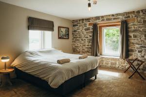 a bedroom with a bed and a stone wall at La Source du Lodji by WelcHome in Spa