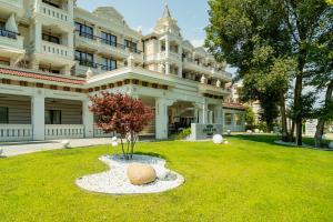 a large white building with a tree in the yard at Green Life Apartments Sozopol in Sozopol