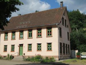 拜尔斯布龙Ferienwohnung-Schoenmuenzblick-Urlaub-im-Nationalpark-Schwarzwald-Schwarzwald-Plus-inklusive的一座有着绿色和红色窗户的白色大楼