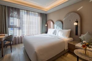 a bedroom with a large white bed and a desk at Mercure Xi'an History Museum in Xi'an