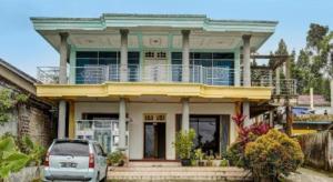 a house with a balcony on top of it at Hotel O Penginapan Aina Syariah in Rantaupanjang