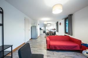 Una sala de estar con un sofá rojo y una cocina. en Appartement Aigueblanche, en La Lechere