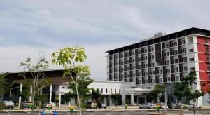 a large building with cars parked in a parking lot at Hotel Scholar's Suites in Kampong Jalan Berop