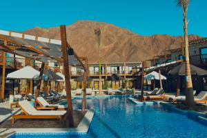 a hotel with a pool with chairs and umbrellas at Crazy Horse Camp in Nuweiba