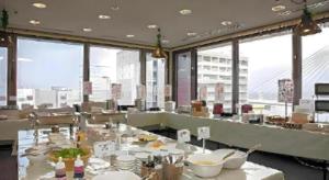 a room with a table with food on it with windows at Sunroute Aomori Hotel in Aomori
