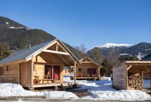 a couple of wooden cabins in the snow at Huttopia Bourg St Maurice in Bourg-Saint-Maurice