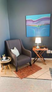 a living room with a chair and a table at Creative 2 Level Townhouse Near City and Wine Route in Brackenfell