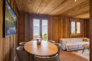 Una sala de estar con una mesa y sillas y un sofá. en Chalet Reine - Belle vue Mont-Blanc, en Combloux