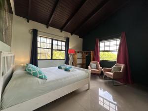 a bedroom with a bed and a chair and windows at Woodstock Palmresort Curacao - Iguana Kamer in Santa Catharina
