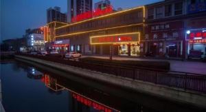 a city street with buildings and a river at night at Shell Changzhou Yangrong City Hotel in Changzhou