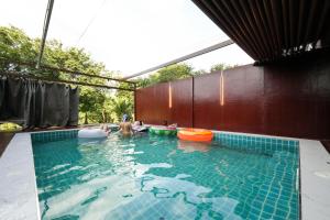 une piscine avec deux frisbees et des gens dedans dans l'établissement 19 Degrees Resort, à Sai Yok